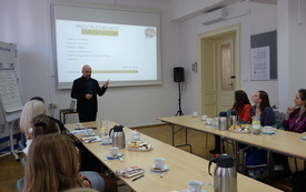 Widok sali szkoleniowej i prowadzącego stojącego przed ekranem