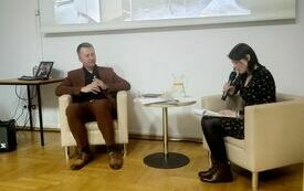 Kobieta i mężczyzna siedzą przy stoliku i rozmawiają.