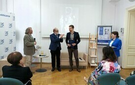 Profesor, dw&oacute;ch potomk&oacute;w pisarza oraz dyrektorka biblioteki stoją pośrodku sali. 