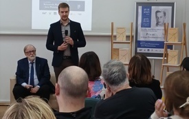 Wnuk pisarza przemawia do mikrofonu.