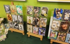 Trzy sztalugi na których wyeksponowano kartki wykonane metodą scrapbookingową