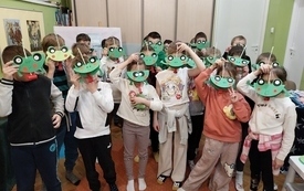 Grupa dzieci z żabkami z papieru pozuje do wspólnego zdjęcia.