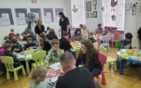 Grupa dzieci z opiekunami wykonuje prace plastyczne