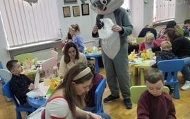 Postać w kostiumie zajączka stoi pośród dzieci