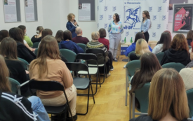 Biblioteczna sala wypełniona publicznością, w głębi dyrektorka biblioteki wita autorkę