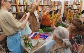 Grupa kobiet składa palmy wielkanocne z kolorowych kwiatów, traw i bukszpanu