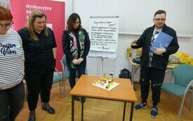 Trzy kobiety i mężczyzna przy stoliku z budowlami z klock&oacute;w Lego. 