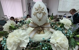 Dekoracja wielkanocna z kwiatów i ozdobionej pisanki.