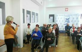 Kobieta z mikrofonem w ręku przemawia do zabranej publiczności