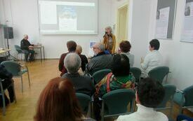 Kobieta z mikrofonem w ręku stoi przed zebraną publicznością