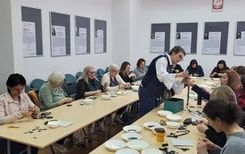 Przy stolikach siedzą uczestnicy warsztatów