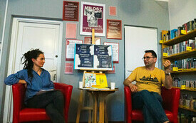 Na fotelach siedzą bibliotekarka i pisarz, rozmawiają.