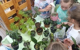 Dzieci przy stole z kwiatami doniczkowymi.