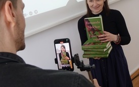 Nagrywanie filmiku z udziałem bibliotekarki z książkami. 
