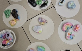 Na podstawkach kolorowe kamyczki, pomalowane farbami przez dzieci.