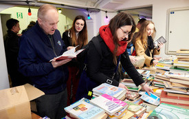 Czytelnicy szukający książek na kiermaszu.