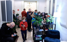 Rodziny z dziećmi rozwiązują zagadki gry bibliotecznej w korytarzu biblioteki.
