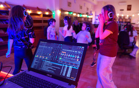 Silent disco w czytelni. Uczestnicy tańczą ze słuchawkami na uszach. 