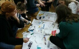 Na dużych arkuszach papieru uczestnicy wyklejają hasła z gazet.