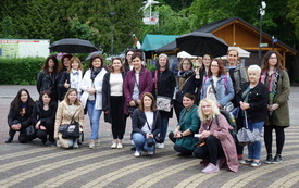 Grupa kobiet pozuje do wspólnej fotografii, dwie z nich trzymają w ręku parasole.