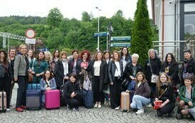 Grupa kobiet z walizkami pozuje do wsp&oacute;lnej fotografii. 