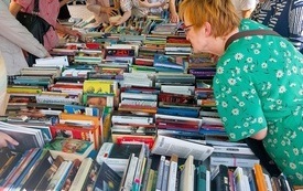 Stoisko z książkami, czytelnicy wyszukujący ze stosów.