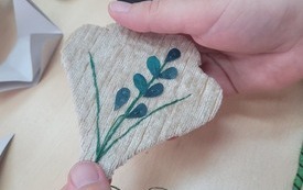 W dłoniach trzymany naszyjnik haftowany.