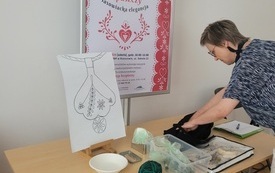 Kobieta rozkłada na stole materiały do haftowania.