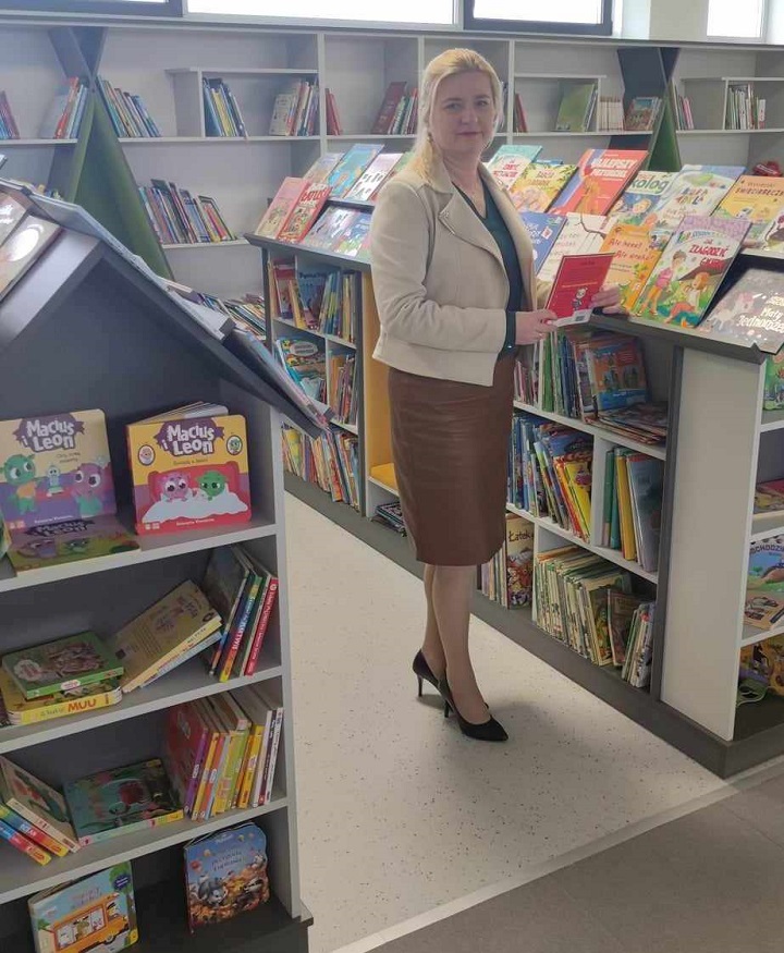 Anita Fal, dyrektor Gminnej Biblioteki Publicznej w Krościenku Wyżnym pozuje do zdjęcia stojąc między półkami z książkami dla dzieci