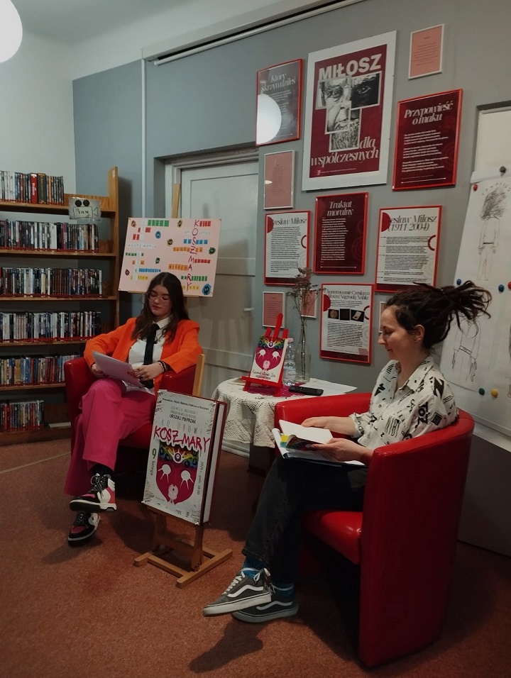 Dwie młode kobiety siedzą na czerwonych fotelach trzemając w dłoniach książki