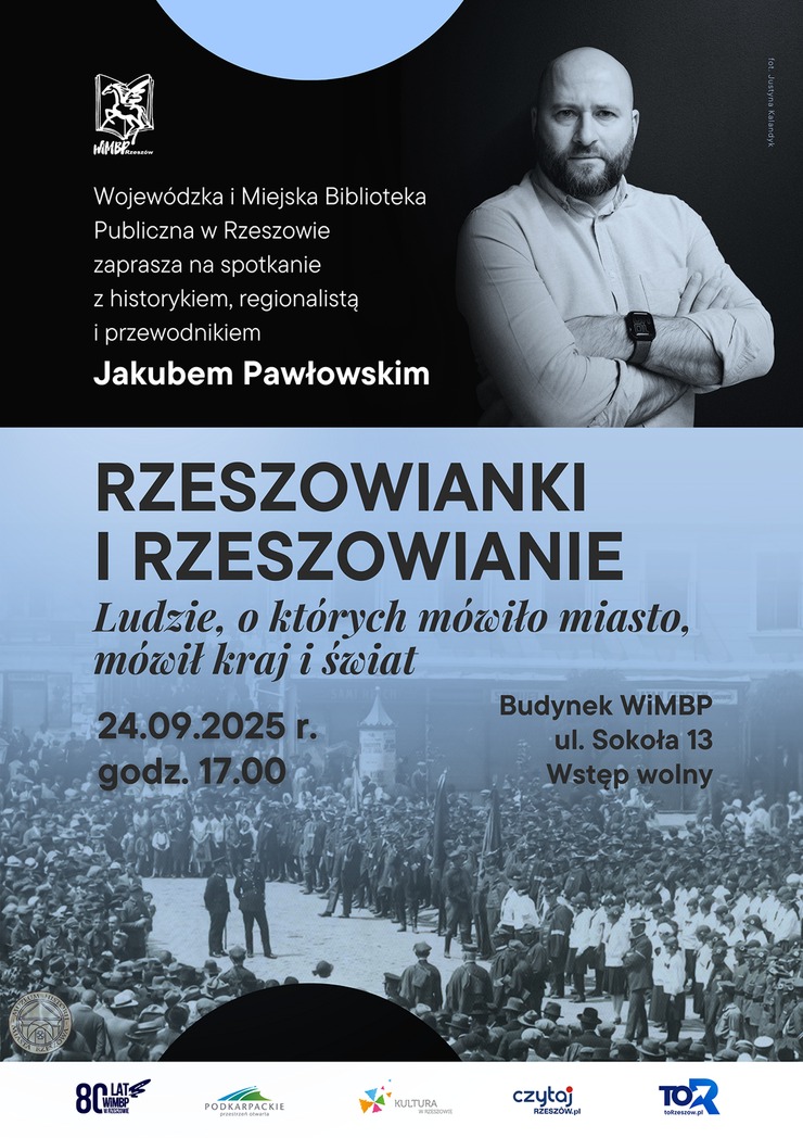 Mężczyzna z zarostem w białek koszuli z założonymi rękami. Poniżej ludzie zebrani na placu